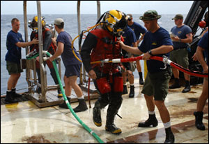 Crew members help divers prepare for their dive