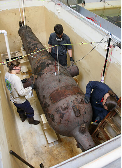 conservators study a cannon of the monitor