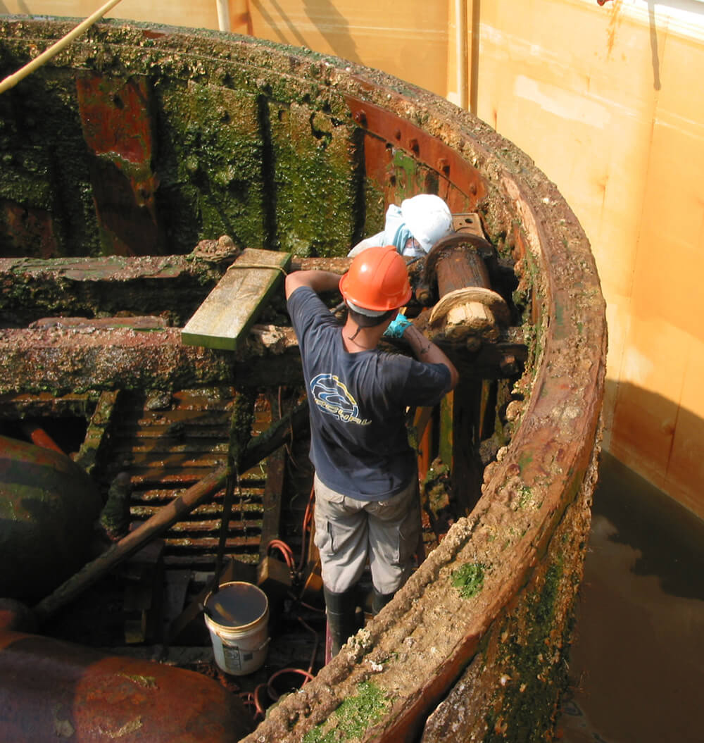 conservators work on the turret ring of the monitor