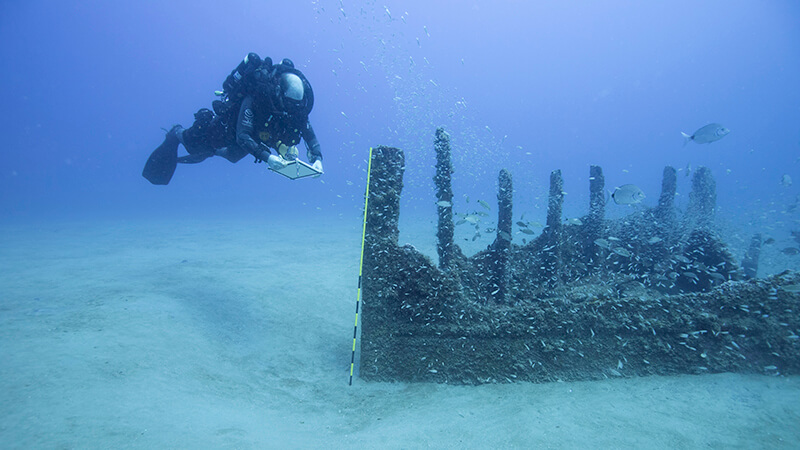 A diver takes measurements of a shipwreck