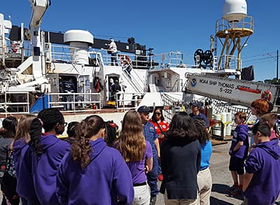 students standing on a dock next the noaa ship thomas jefferson