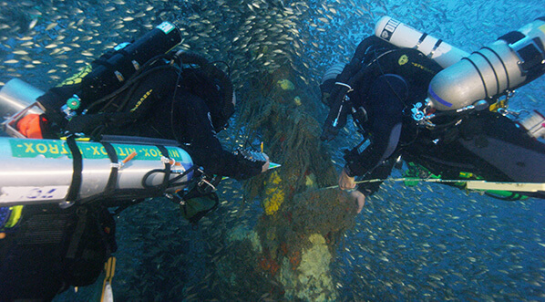Divers examen a part of the Merak covered in marine growth
